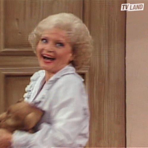 Woman Smiling Holding Teddy Bear in Front of TV Land Door