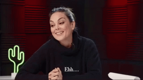 Woman Smiling in Black Sweater Near Neon Cactus