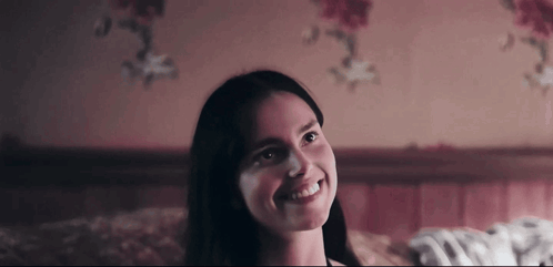 Woman Smiling on Bed in Dark Room
