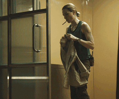 Woman Smoking Cigarette in Front of Glass Door
