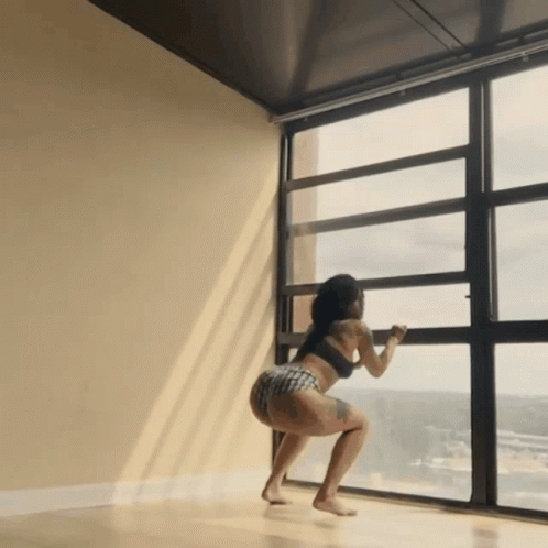 Woman Squatting by Large Window Looking Out