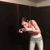 Woman Standing In Dark Room Drinking From Glass GIF
