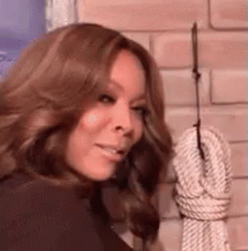 Woman Standing In Front Of Hanging Rope On Brick Wall GIF