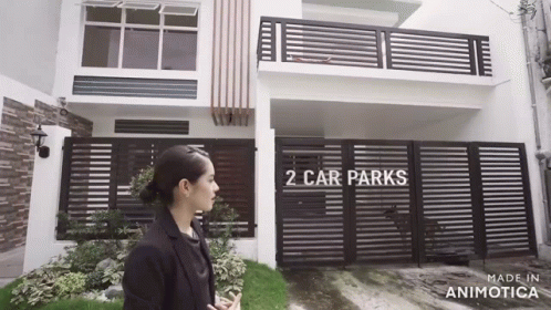 Woman Standing in Front of House With Fence and Car Park