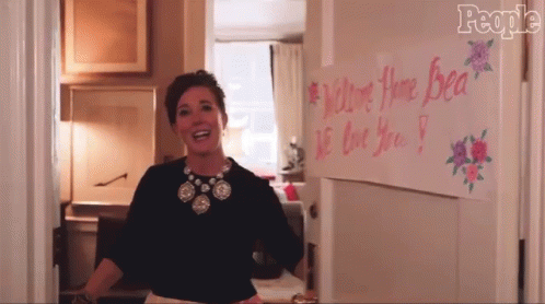 Woman Standing In Front Of We Love You Bea Sign GIF