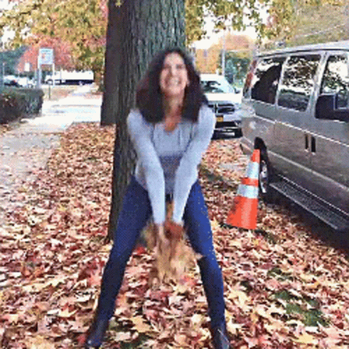 Woman Standing in Pile of Leaves Next to Van