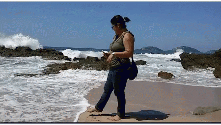 Woman Standing On Beach Looking At Phone GIF