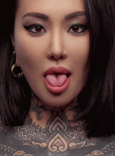 Woman Sticking Tongue Out With Nose Ring and Chest Tattoo