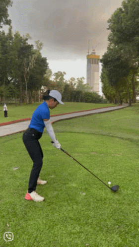 Woman Swinging Golf Club at Ball
