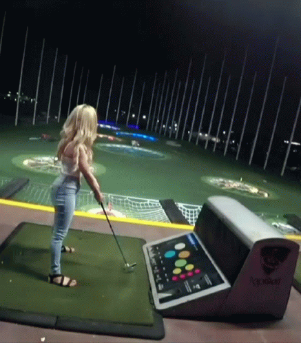 Woman Swinging Golf Club on Golf Course at Night