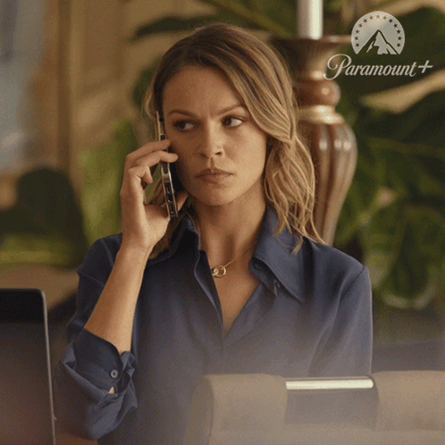 Woman Talking On Phone In Front Of Paramount Sign GIF