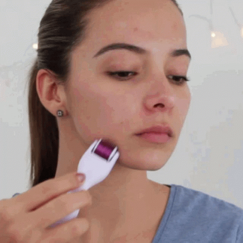 Woman Using Face Roller in Blue Shirt