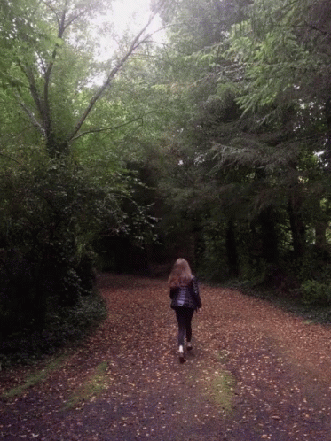 Woman Walking Down Dirt Road In Woods GIF