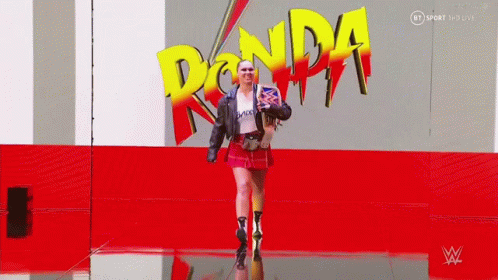 Woman Walking in Front of Ronda Logo