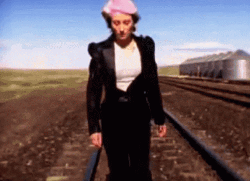 Woman Walking Train Tracks Wearing Hat