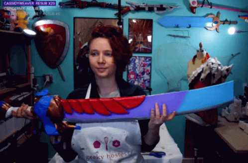 Woman Wearing Geeky Hostess Apron Holding Large Sword