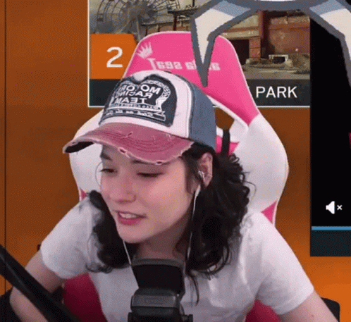 Woman Wearing Hat That Says No Om Misar Sits in Chair
