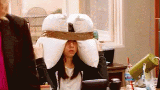 Woman Wearing Pillow on Head at Desk