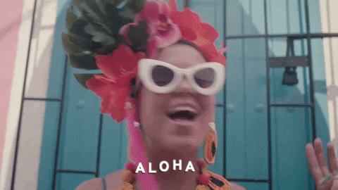 Woman Wearing Sunglasses and Flowered Headpiece Says Aloha