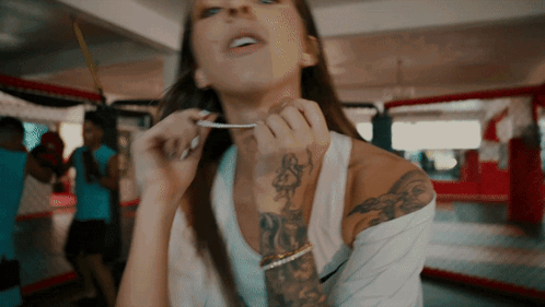 Woman With Arm Tattoo Holding Something in Mouth