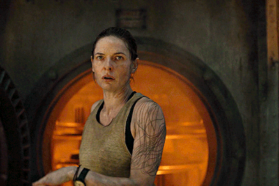 Woman With Arm Tattoo Standing in Front of Orange Door