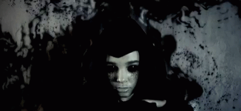 Woman With Black Eyes And Black Hat In Dark Room GIF