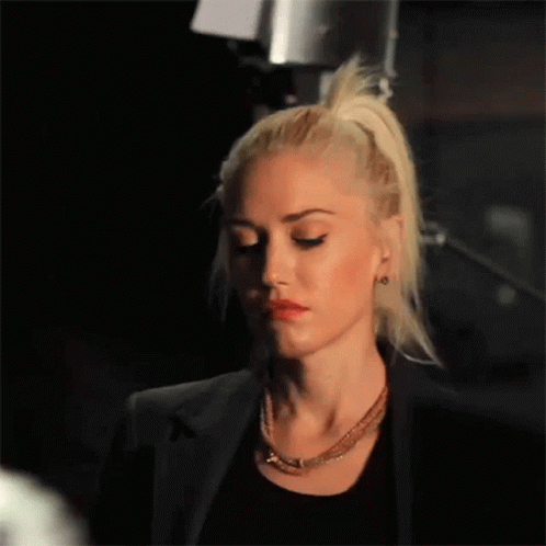 Woman With Blonde Hair In Black Jacket And Necklace GIF