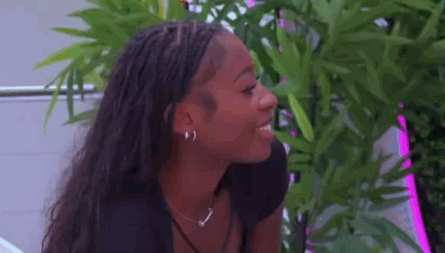 Woman With Braids and Plant Looking at Camera