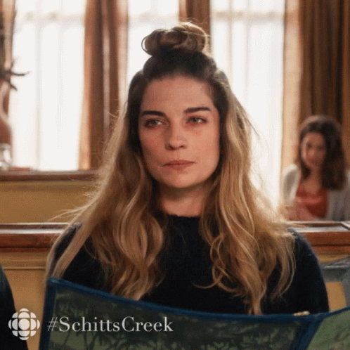 Woman With Bun Holding Schitt's Creek Book GIF