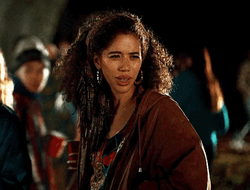 Woman With Curly Hair In Brown Jacket And Earrings In Crowd GIF