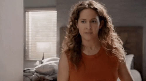Woman With Curly Hair in Front of Bed