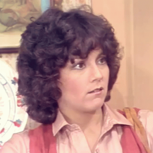 Woman with Curly Hair in Pink Shirt and Red Vest