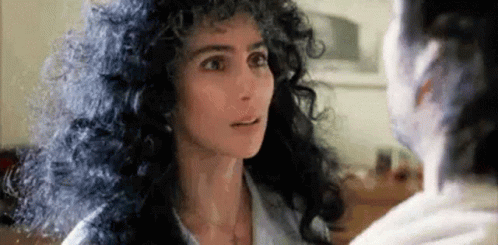 Woman With Curly Hair Looking at Another Woman in Mirror