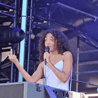 Woman With Curly Hair Singing Into Microphone GIF