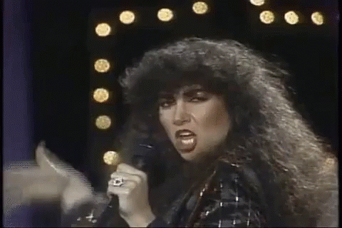 Woman With Curly Hair Singing Into Microphone GIF