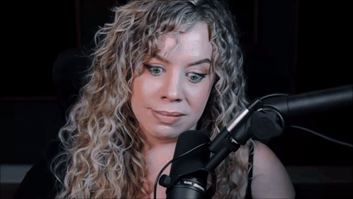 Woman With Curly Hair Talking Into Microphone