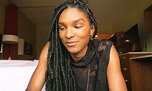 Woman With Dreadlocks Sitting On Bed Looking Down GIF