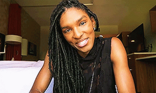 Woman With Dreadlocks Sitting On Bed Smiling GIF