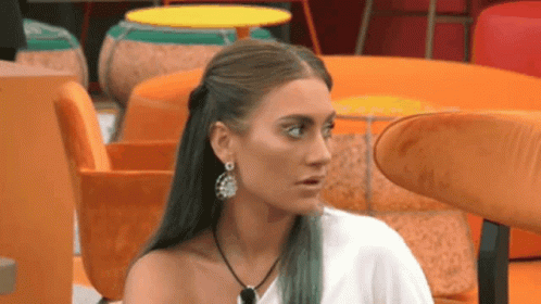 Woman with Earrings and Necklace Sitting in Room with Orange Chairs