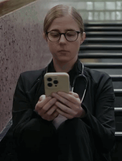 Woman With Glasses And Stethoscope Sitting On Stairs Looking At Cell Phone GIF