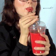 Woman With Glasses Drinks From Red Cup With Straw