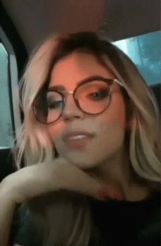 Woman With Glasses Hand On Chin In Car GIF