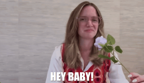 Woman with Glasses Holding Flower Saying Hey Baby