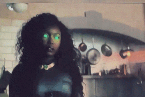 Woman With Green Eyes In Kitchen With Hanging Pots And Pans GIF