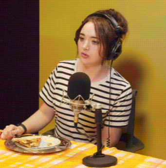 Woman With Headphones and Plate of Food at Microphone