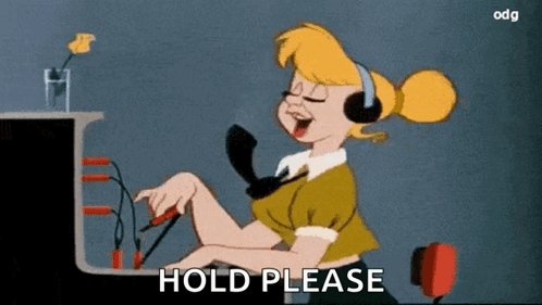 Woman With Headphones At Desk Saying Hold Please GIF