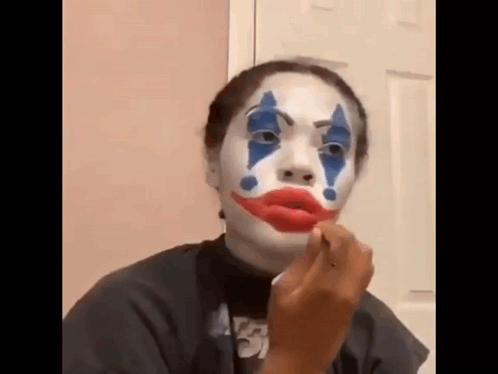 Woman With Joker Face Paint Applying Lipstick