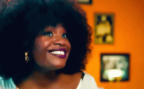 Woman With Large Afro Smiling in Front of Picture Wall
