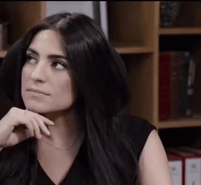 Woman With Long Black Hair Sitting in Front of Bookshelf