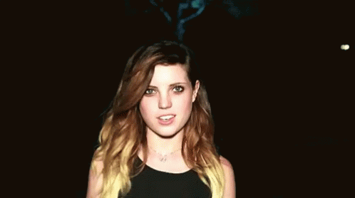 Woman With Long Brown Hair Smiling In Dark Room GIF